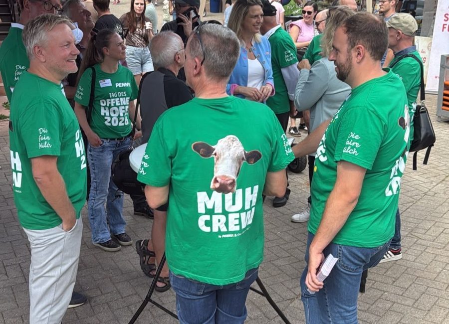 Eine Gruppe von Menschen in grünen Muh Crew-T-Shirts unterhält sich bei einer Veranstaltung im Freien zum Thema Automatischer Entwurf.